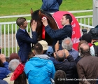 Il lad Lorenzo Battista aiuta il trainer Marco Botti a sistemare la coccarda del vincitore nella capezza di Dylan Mouth